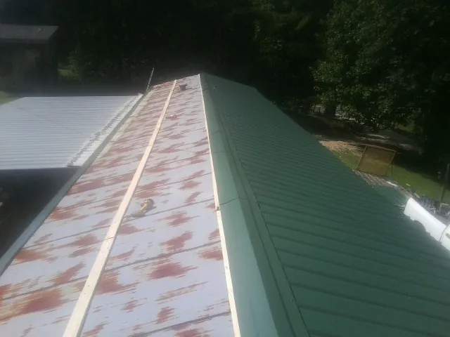 Old rusted panels beside newly installed green metal roofing — Wind Damage Roof Repair by Roofing Brothers in Parsons