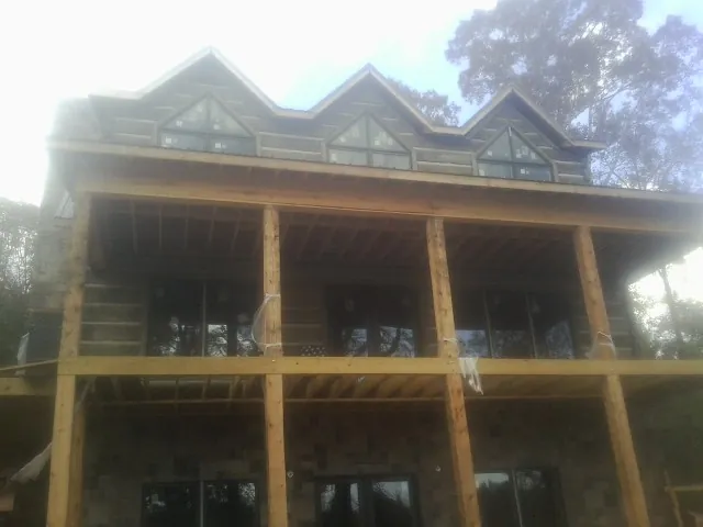 Dormers and porch framing on a large log home under construction — Roof Coating work by our crew in Parsons