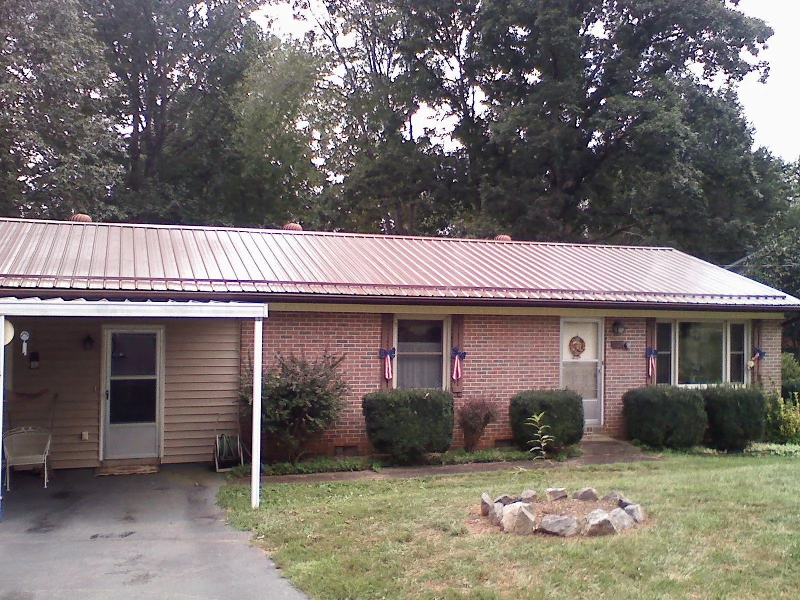 Bronze metal roof and carport on a brick ranch home — Roof Repair work by our crew in Parsons